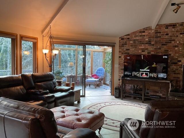 living room with vaulted ceiling with beams, a wealth of natural light, and light tile patterned flooring