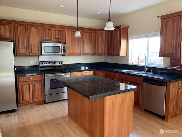 kitchen featuring light hardwood / wood-style flooring, a center island, decorative light fixtures, stainless steel appliances, and sink