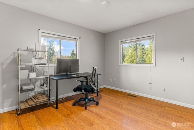 home office with light wood-type flooring and plenty of natural light