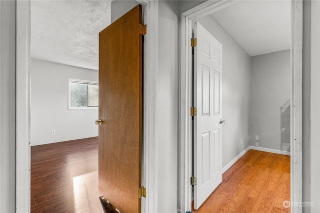 hallway featuring a textured ceiling and light hardwood / wood-style floors