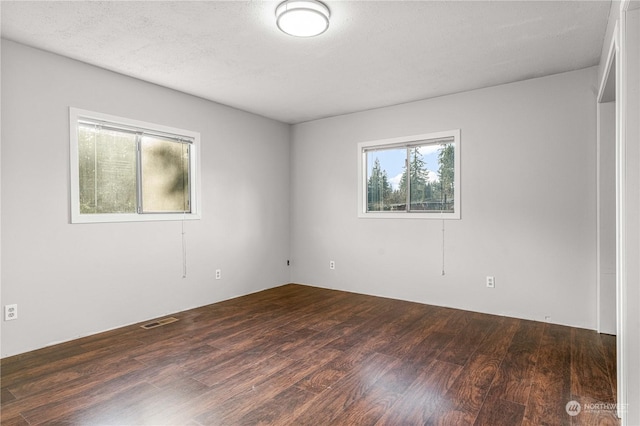 unfurnished room with a textured ceiling and dark hardwood / wood-style floors