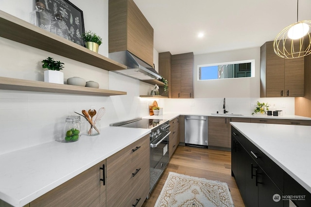 kitchen with stainless steel appliances, decorative backsplash, pendant lighting, light hardwood / wood-style flooring, and sink