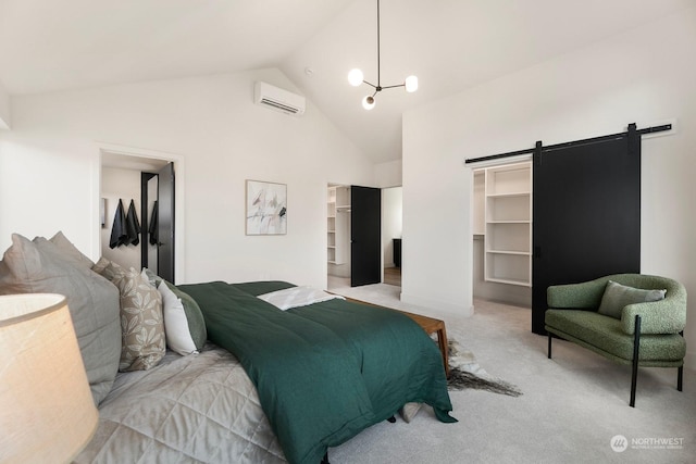 carpeted bedroom with a barn door, a notable chandelier, a wall unit AC, a walk in closet, and a closet