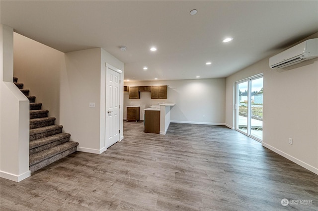 unfurnished living room with hardwood / wood-style flooring and a wall mounted air conditioner