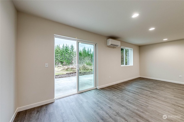 spare room featuring a wall mounted AC and light hardwood / wood-style flooring