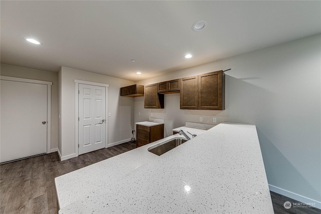 kitchen with light stone counters, dark hardwood / wood-style flooring, and sink