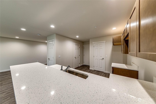 kitchen featuring dark hardwood / wood-style flooring, light stone countertops, and sink