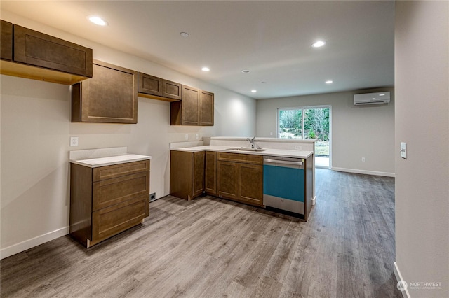 kitchen with an AC wall unit, sink, stainless steel dishwasher, kitchen peninsula, and light wood-type flooring