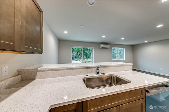 kitchen with sink, kitchen peninsula, dishwasher, a wall unit AC, and light stone countertops