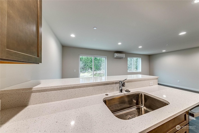 kitchen featuring light stone countertops, sink, and a wall unit AC