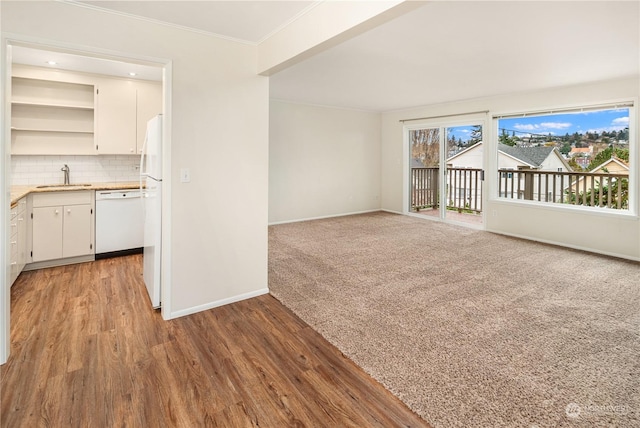 unfurnished living room with light hardwood / wood-style floors, sink, and ornamental molding