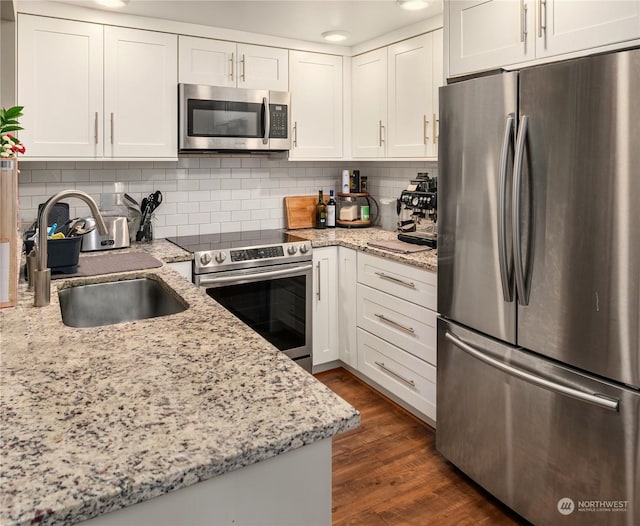 kitchen with tasteful backsplash, sink, white cabinetry, appliances with stainless steel finishes, and dark hardwood / wood-style flooring