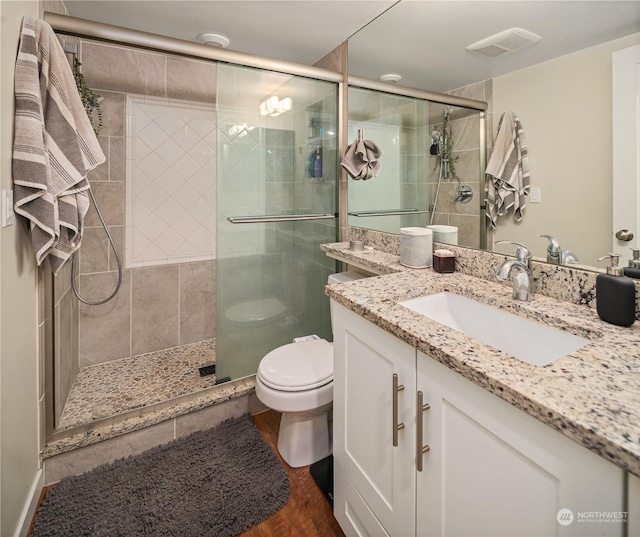 bathroom featuring walk in shower, vanity, toilet, and hardwood / wood-style flooring