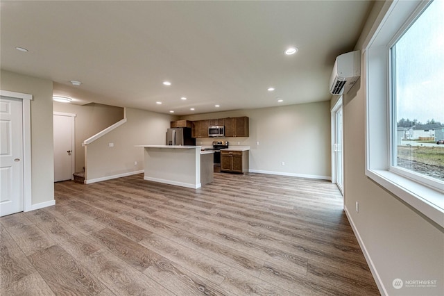 unfurnished living room with light wood-type flooring and an AC wall unit