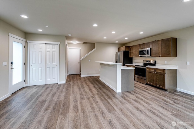 kitchen featuring light hardwood / wood-style flooring, appliances with stainless steel finishes, and a center island with sink