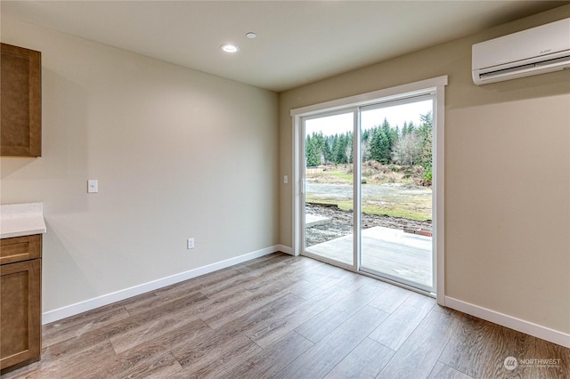 unfurnished dining area with a wall mounted AC and light hardwood / wood-style flooring