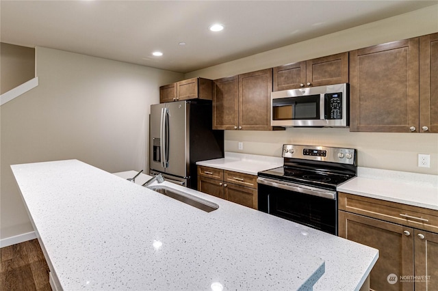 kitchen with dark wood-type flooring, appliances with stainless steel finishes, sink, and light stone counters