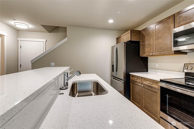 kitchen featuring appliances with stainless steel finishes, light stone counters, and sink