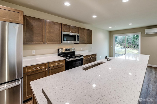 kitchen with stainless steel appliances, sink, dark hardwood / wood-style flooring, light stone counters, and a center island