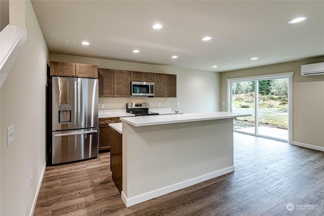 kitchen featuring a center island with sink, appliances with stainless steel finishes, dark hardwood / wood-style flooring, an AC wall unit, and sink