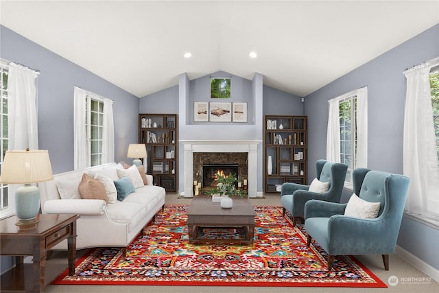 living room featuring lofted ceiling, a premium fireplace, and carpet floors