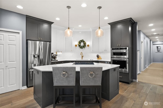 kitchen featuring a kitchen island, hardwood / wood-style flooring, appliances with stainless steel finishes, and hanging light fixtures