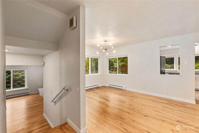 interior space with vaulted ceiling, a chandelier, and a baseboard heating unit