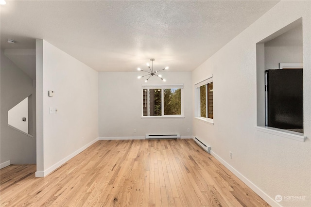 unfurnished room featuring baseboard heating, a textured ceiling, light hardwood / wood-style floors, and a chandelier