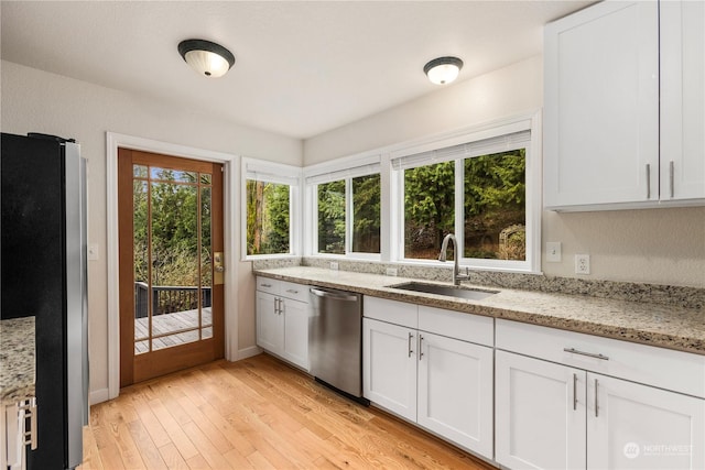 kitchen with stainless steel appliances, light wood-type flooring, light stone countertops, sink, and white cabinetry