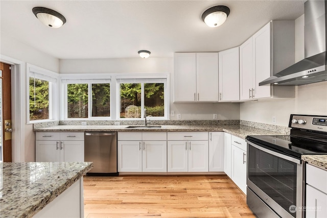 kitchen featuring sink, stainless steel appliances, white cabinetry, and wall chimney range hood