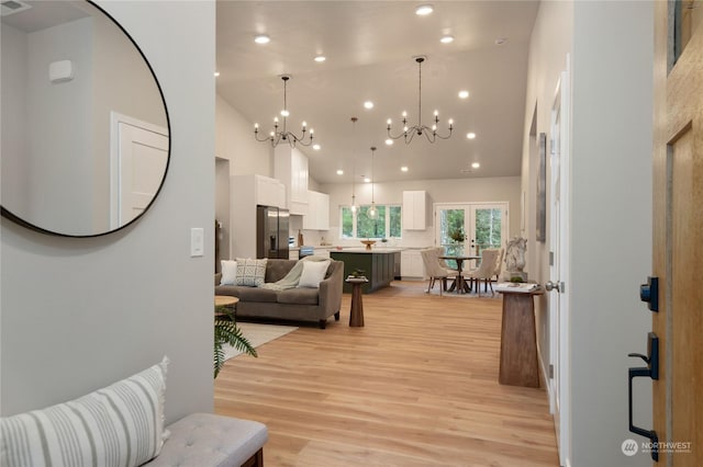 interior space with light wood-type flooring, french doors, high vaulted ceiling, and a chandelier