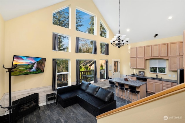 living room featuring high vaulted ceiling, sink, plenty of natural light, and an inviting chandelier