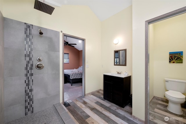 bathroom featuring hardwood / wood-style floors, vanity, toilet, vaulted ceiling, and tiled shower