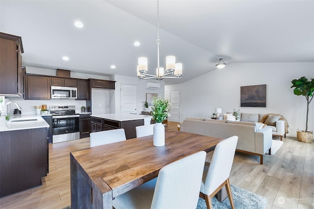 dining room featuring an inviting chandelier, vaulted ceiling, light hardwood / wood-style floors, and sink