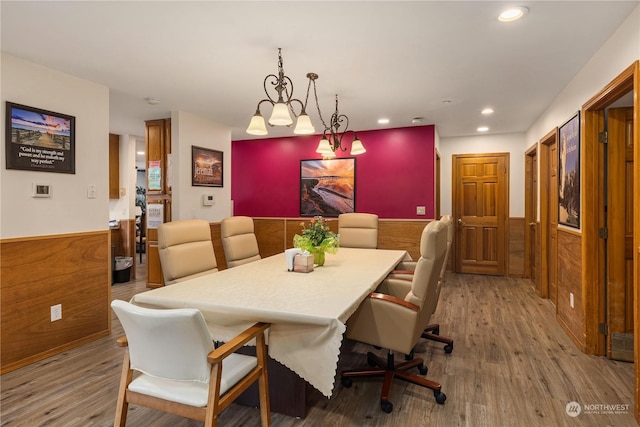 dining room featuring wood-type flooring, an inviting chandelier, and wooden walls