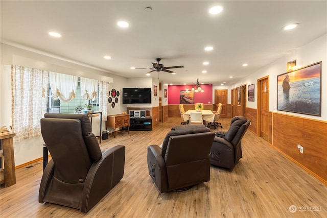 living room with ceiling fan, light hardwood / wood-style flooring, and wood walls