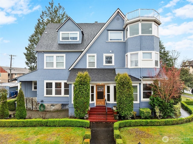 view of front of house featuring a front yard and a shingled roof