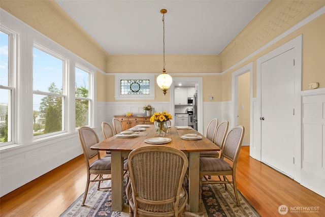 dining area featuring light wood-type flooring and a wainscoted wall