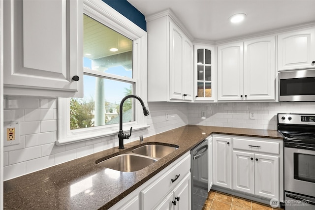 kitchen featuring white cabinetry, backsplash, appliances with stainless steel finishes, and a sink