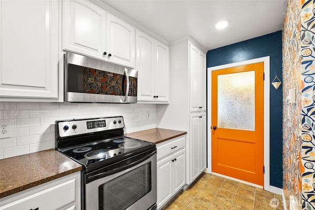 kitchen featuring backsplash, dark countertops, white cabinetry, stainless steel appliances, and baseboards