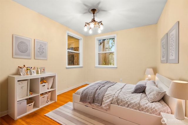 bedroom featuring baseboards, an inviting chandelier, and wood finished floors