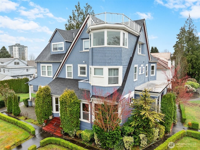 shingle-style home with a balcony and roof with shingles