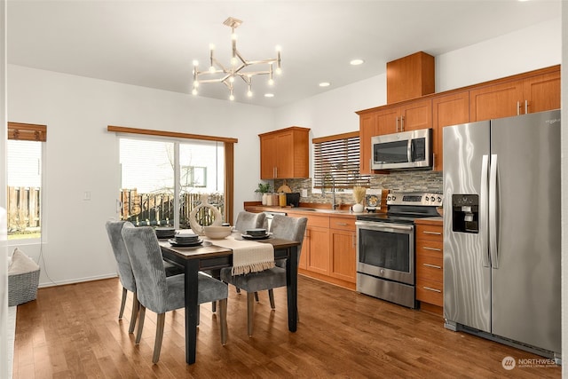 kitchen featuring sink, dark hardwood / wood-style flooring, decorative backsplash, stainless steel appliances, and plenty of natural light