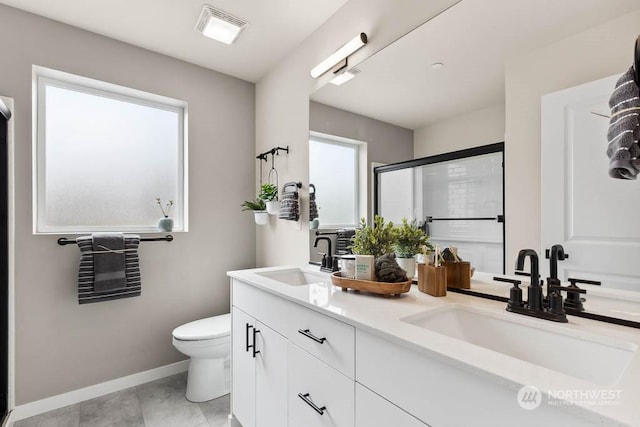 bathroom featuring toilet, vanity, a shower with shower door, and a healthy amount of sunlight