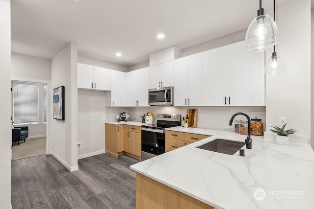 kitchen featuring stainless steel appliances, pendant lighting, light stone counters, white cabinets, and sink