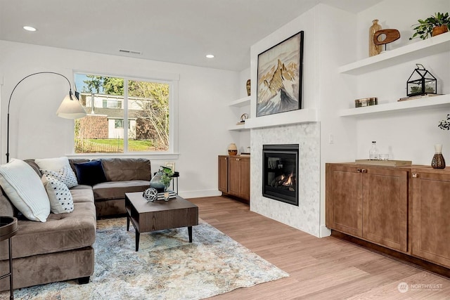 living room featuring built in features and light hardwood / wood-style floors