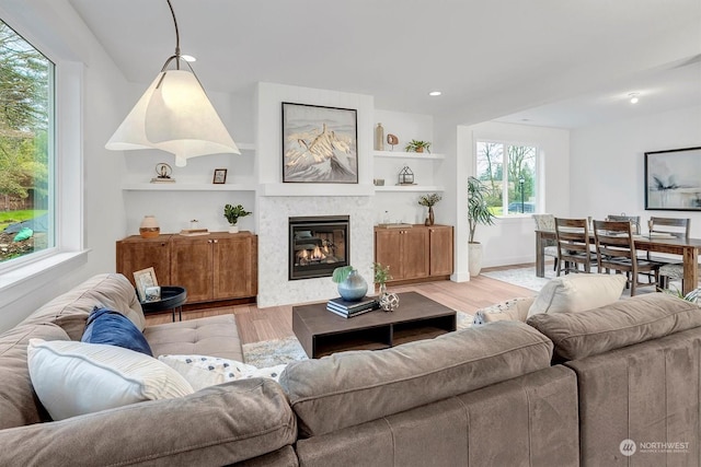 living room featuring built in features and light hardwood / wood-style flooring