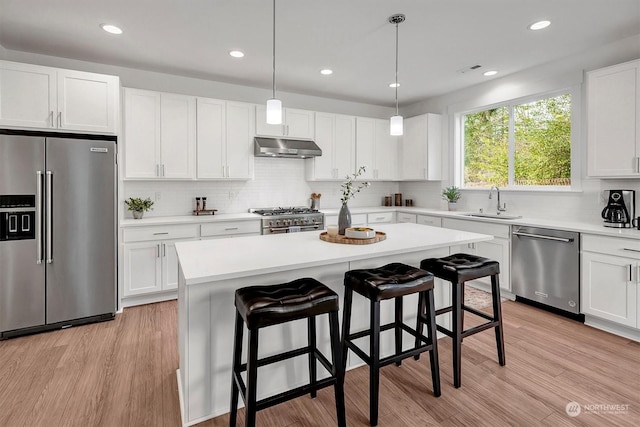 kitchen featuring a center island, high end appliances, hanging light fixtures, light wood-type flooring, and white cabinets