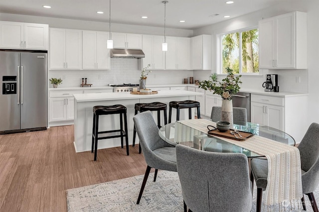 kitchen featuring white cabinets, light wood-type flooring, stainless steel appliances, and pendant lighting