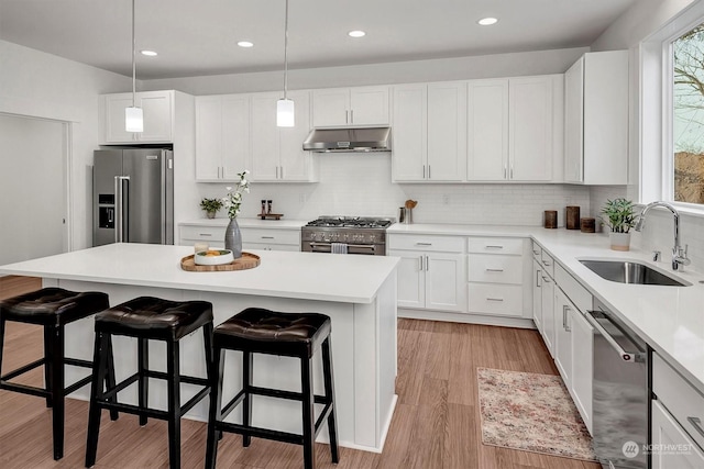 kitchen featuring white cabinetry, high end appliances, a kitchen island, a breakfast bar, and sink